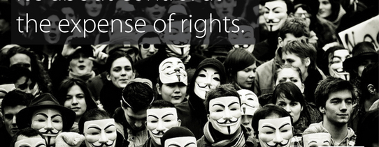 Auf dem Bild tragen fast alle Menschen eine Guy-Fawkes-Maske und oben links steht "TTIP isn't about trade. It's about control at the expense of rights.".