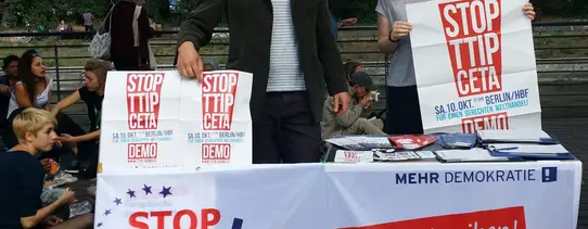 (Aktion in Berlin am Maybachufer | Foto by Mehr Demokratie | Lizenz: CC BY-SA 2.0) Ein Infostand gegen TTIP und CETA von Mehr Demokratie ist zu sehen.