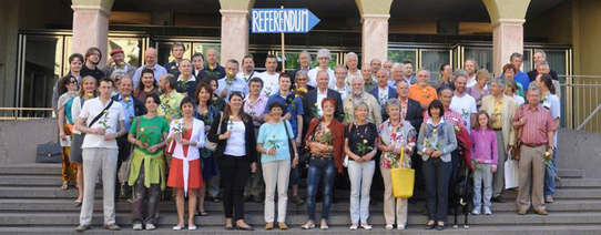 Circa 40 Menschen stehen auf einer Treppe und im Hintergrund hält jemand ein Schild hoch, mit der Aufschrift "REFERENDUM".