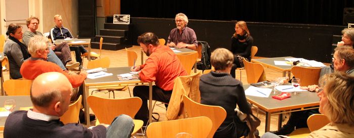 2013-06-13 Veranstaltung in Singen Auf dem Bild sind kleine Tischgruppen mit sitzenden Menschen daran und vorne sind zwei Menschen, welche reden.