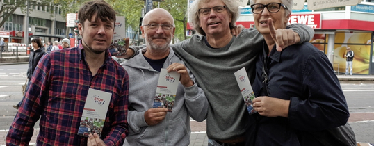 Vier Menschen stehen mit Flyern gegen TTIP auf dem Bild.