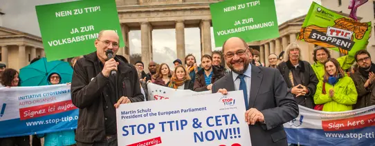 Martin Schulz steht vor dem Brandenburger Tor mit Menschen die Protestieren.