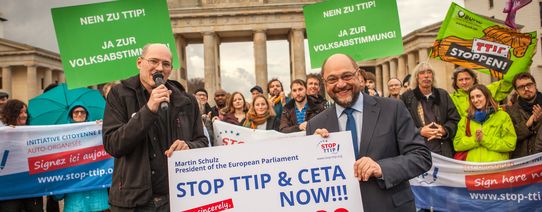 Martin Schulz steht vor dem Brandenburger Tor mit Menschen die Protestieren.