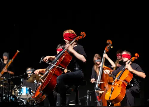 © Navina Neuschl Zu sehen ist ein Orchester, welches mit verbundenen Augen spielt.