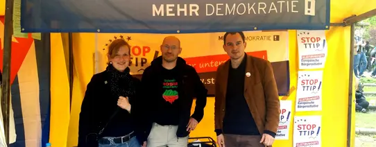 (Anti-TTIP-Aktion beim MyFest in Berlin am 1. Mai 2015 | v.l.: Regine Laroche, Dr. Michael Efler, Charlie Rutz | Foto by Kurt Wilhelmi | CC BY-SA 2.0) Ein Infostand von Mehr Demokratie gegen TTIP.