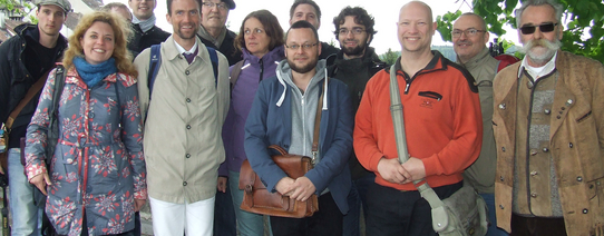 (Teilnehmer/innen der Schweiz-Reise | Foto by Cora Pfafferott | Lizenz: CC BY-NC 2.0) Auf dem Bild sieht man 11 Personen, welche alle in die Kamera lächeln.