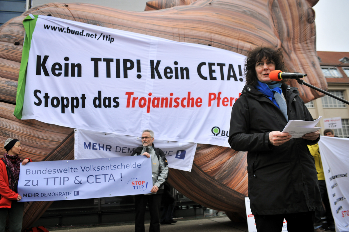 Eine Frau hält vor dem trojanischen Pferd eine Rede.